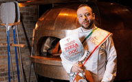 man holding award in front of a pizza oven